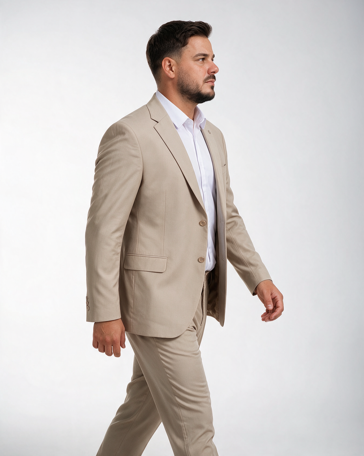 Muškarac u bež dvodelnom odelu sa sakoom na dva dugmeta i klasičnim reverom, slim fit kroja, gleda napred, bočno.