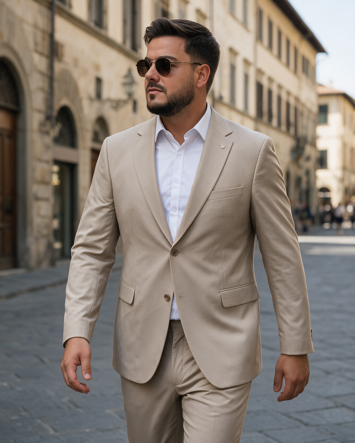 Muškarac u bež slim fit dvodelnom odelu velikih brojeva (60-70) sa dva dugmeta i Costumen značkom, šeta Firencom.