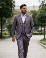 Man in bordo striped three-piece suit walking in a city park.