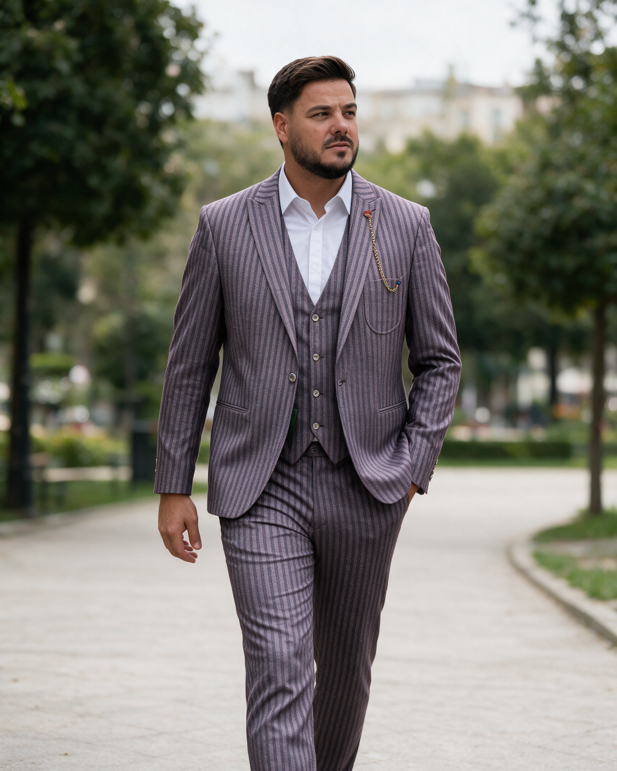 Man in bordo striped three-piece suit walking in a city park.