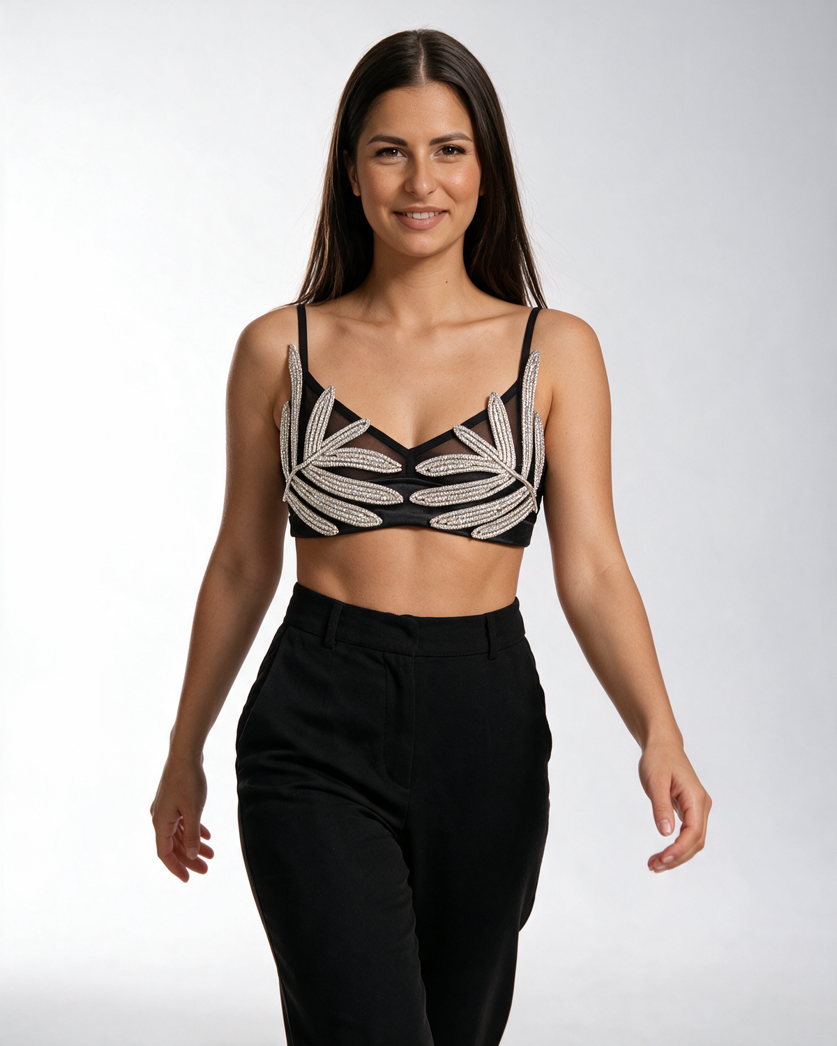 Crni bralet top sa kristalnim listovima, V izrezom i mrežom, nošen sa crnim pantalonama.