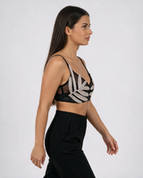 Crni bralet top sa kristalnim listovima, kratak, sa tankim bretelama i V izrezom, nošen uz crne pantalone.