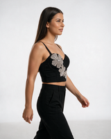 Crni bustier top sa oblikovanim korpicama i kristalnim cvetovima, nošen sa crnim pantalonama.
