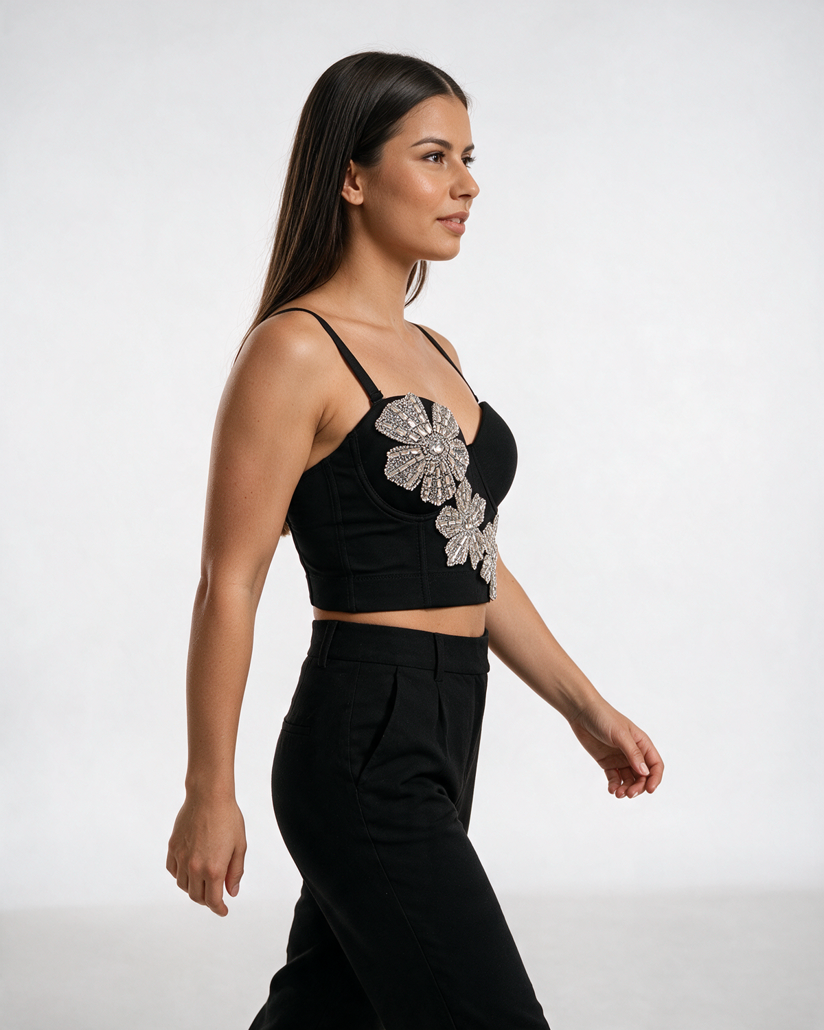 Crni bustier top sa oblikovanim korpicama i kristalnim cvetovima, nošen sa crnim pantalonama.