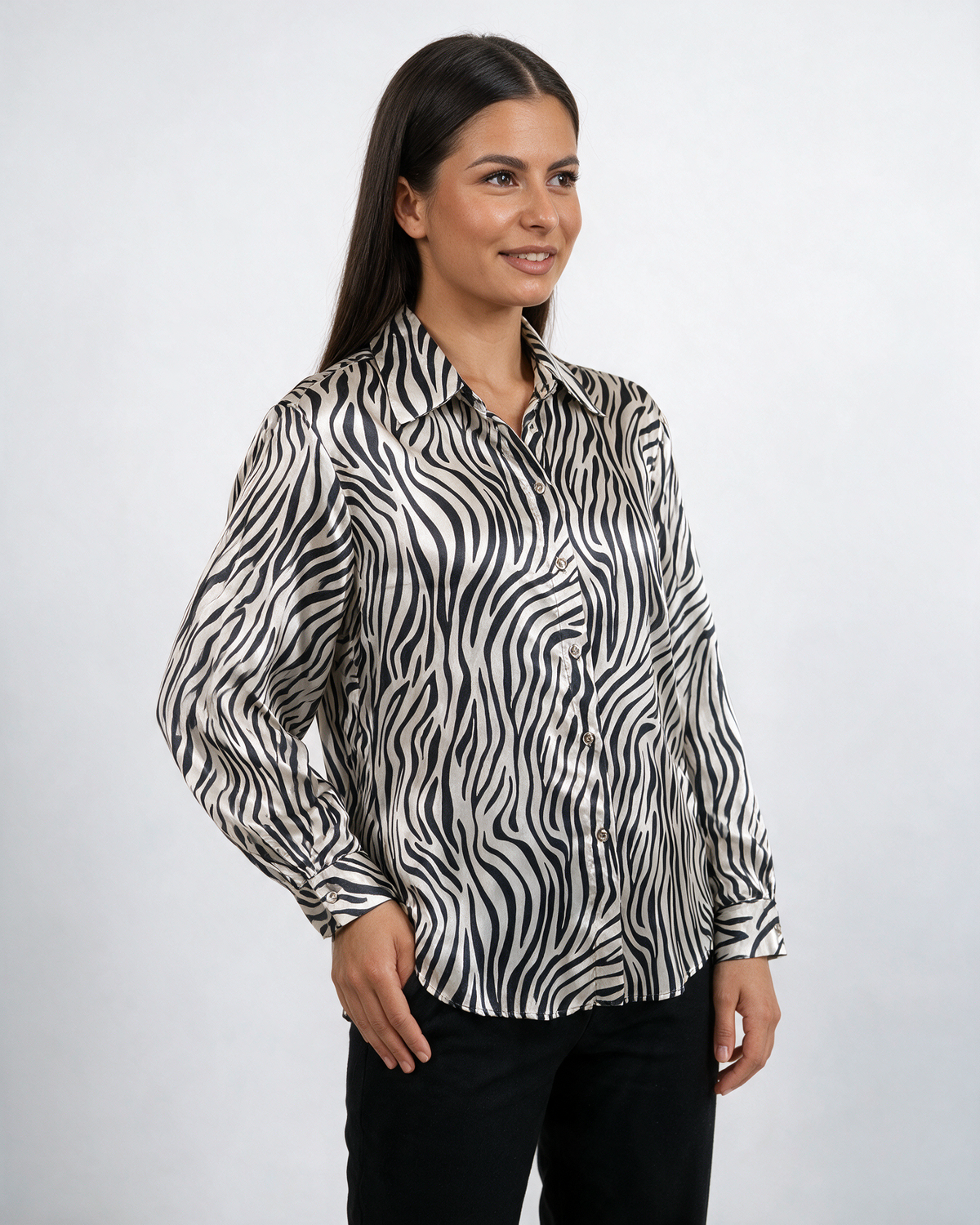 Ženska crno-bela satenska košulja sa zebra printom, klasičnom kragnom i dugim rukavima, nošena sa pantalonama.