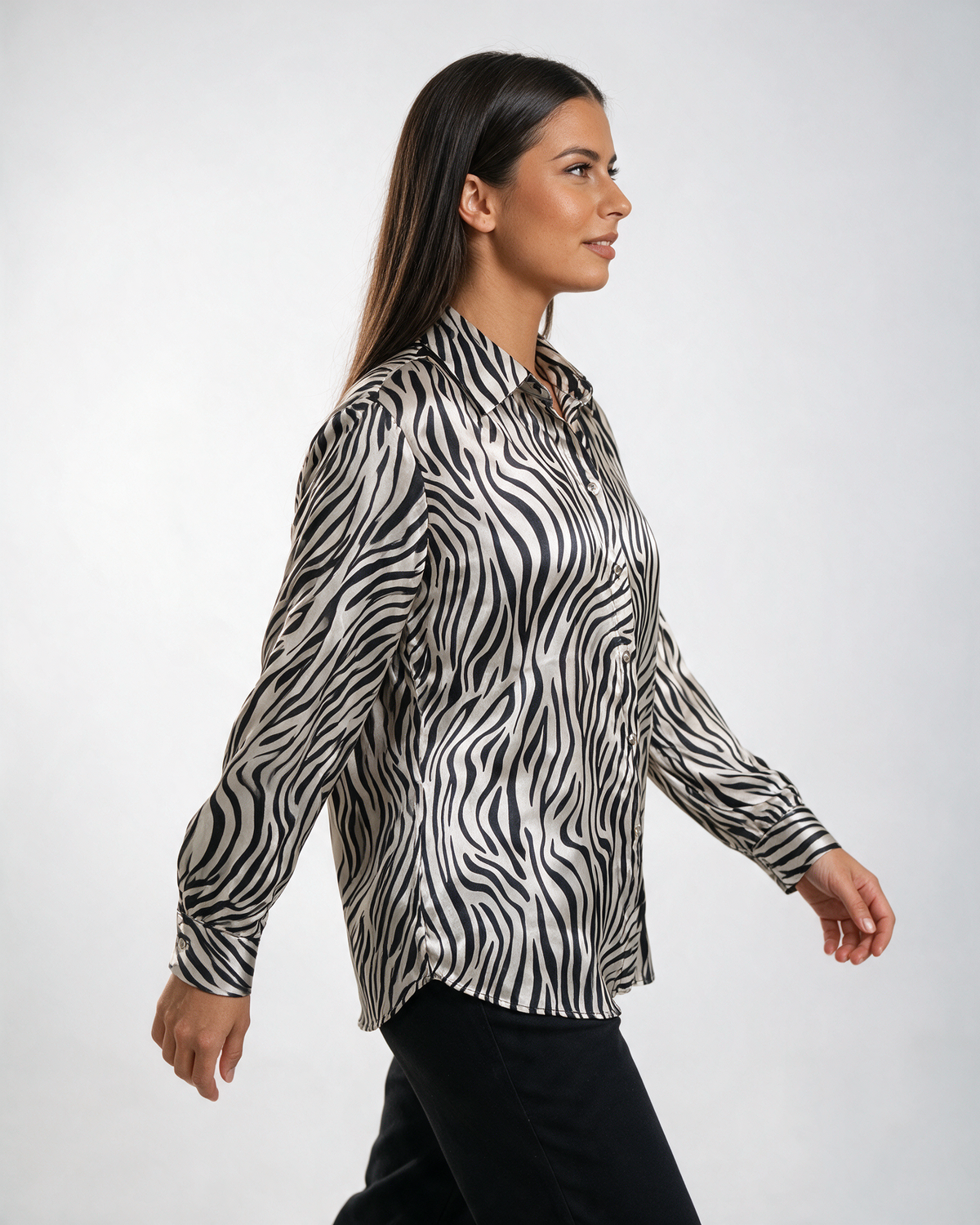Ženska crno-bela satenska košulja sa zebra printom, klasičnom kragnom i dugim rukavima, nošena uz tamne pantalone.