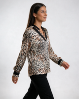 Ženska leopard bluza sa crnim V izrezom i crnim manžetnama, dugih rukava, nošena sa crnim pantalonama.
