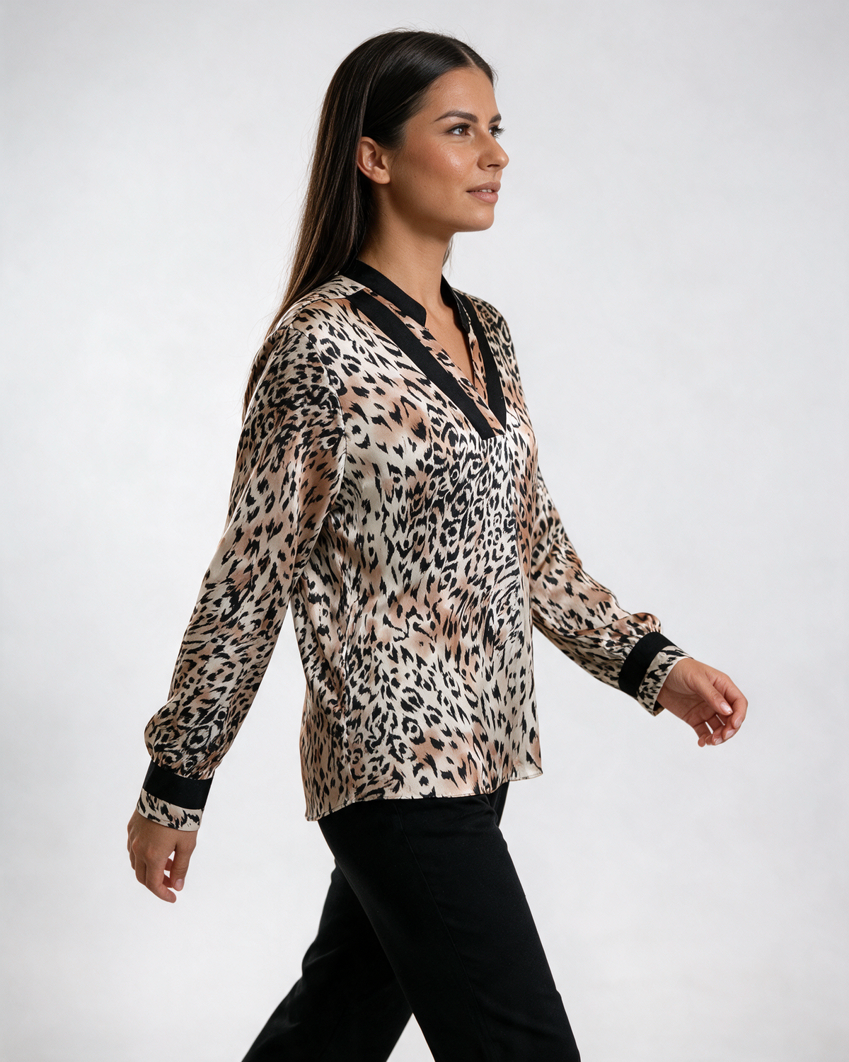 Ženska leopard bluza sa crnim V izrezom i crnim manžetnama, dugih rukava, nošena sa crnim pantalonama.